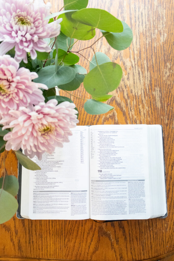 Open bible on table with pink flowers