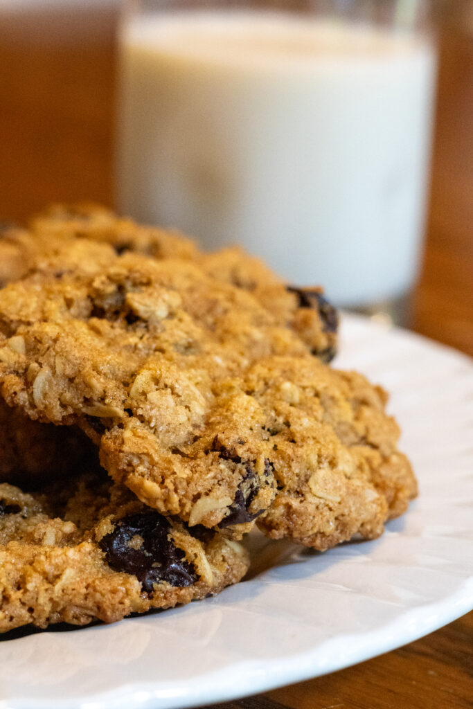 Whole grain oatmeal cookies on a plate with a glass of milk in the background