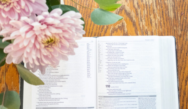 open bible on table with pink flowers in the corner