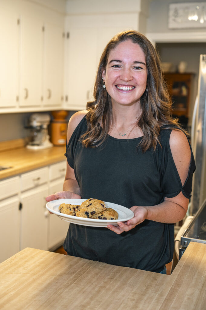 Woman in kitchen holding plate of scones