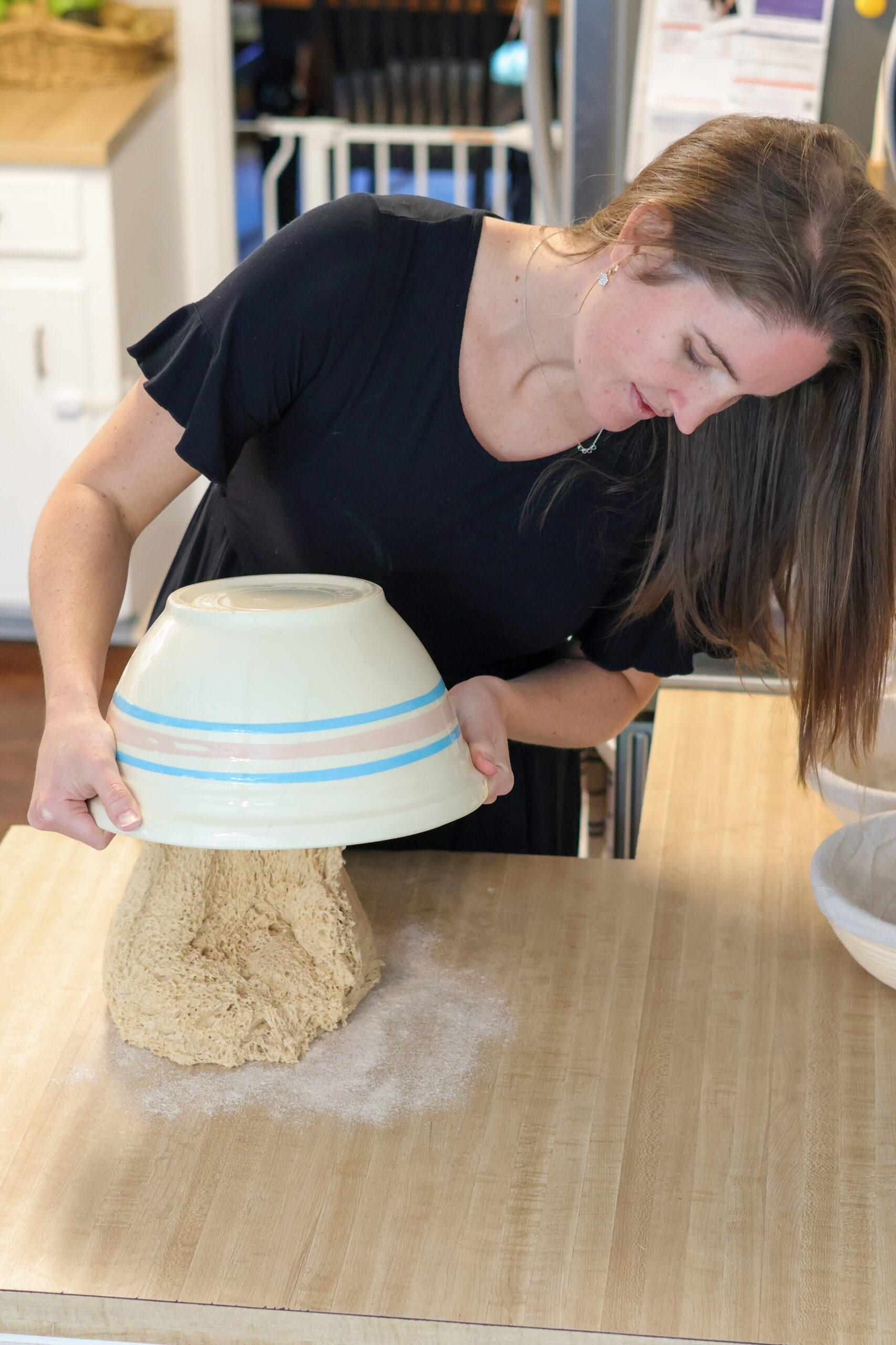 Woman dumping sourdough bread onto counter out of bowl