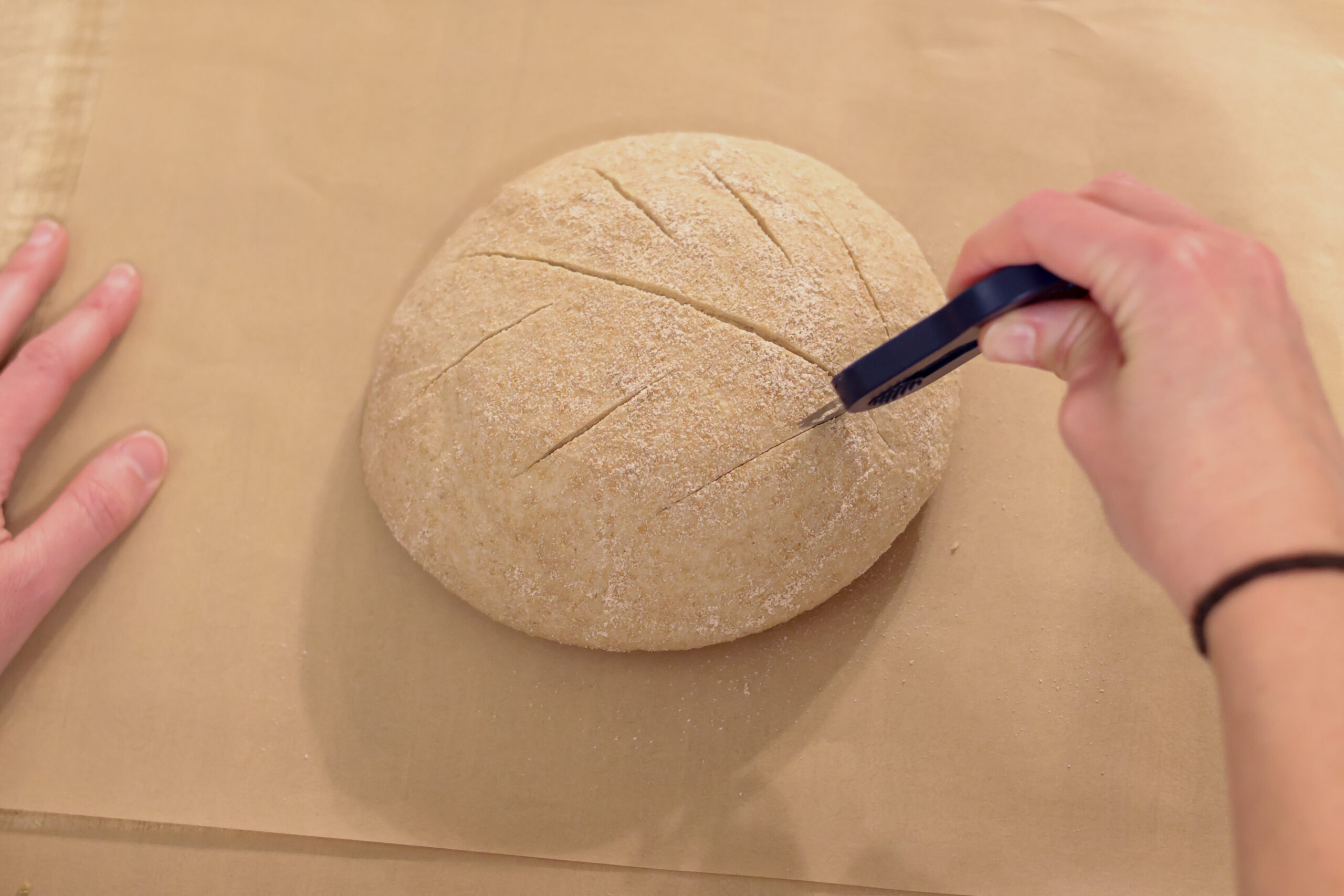 Scoring a loaf of sourdough bread before baking