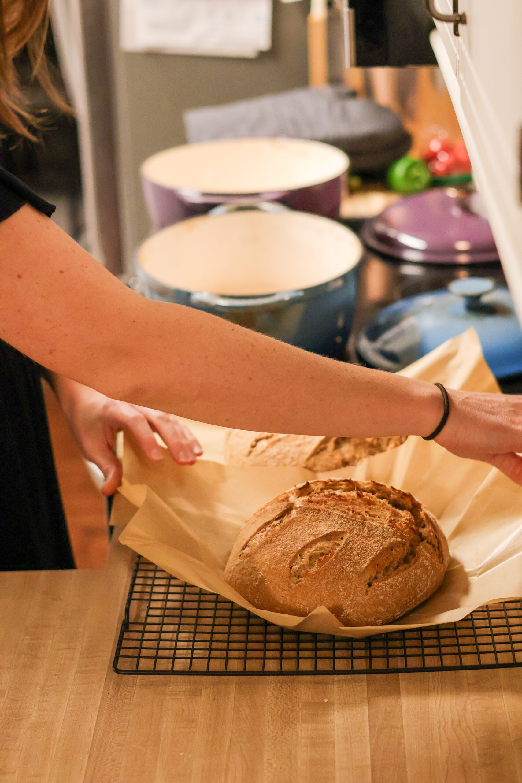 Removing artisan sourdough bread from dutch oven after baking to cooling rack