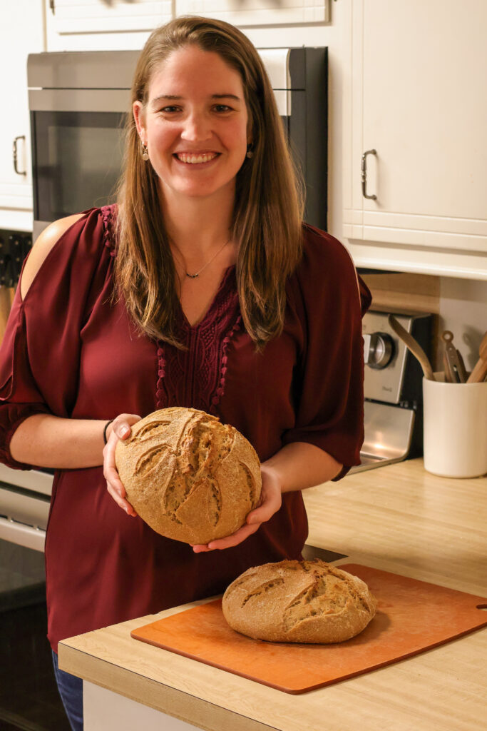 Woman standing in her kitchen holding freshly baked sourdough bread